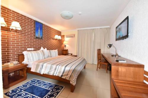 een hotelkamer met een bed en een bureau bij Adamaoua Grand Hôtel Aéroport in Douala