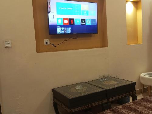 a flat screen tv on a wall with a table at Khayaban-e-Amin Luxurious Apartments in Lahore