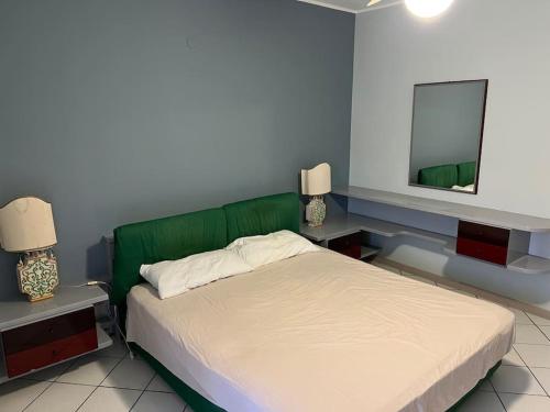 Schlafzimmer mit einem Bett mit einem grünen Kopfteil und einem Spiegel in der Unterkunft Relax Sea Capomulini Appartamento su due livelli in Acireale