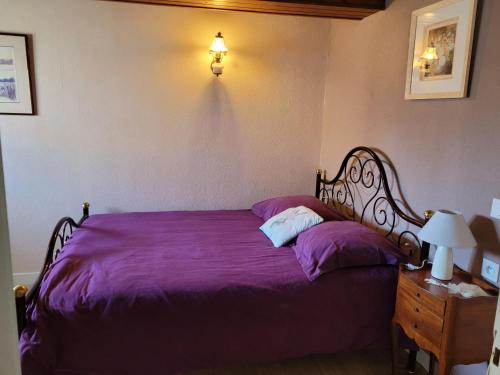 - une chambre avec un lit doté de draps violets et d'une lampe dans l'établissement Charmante maison de vacances, à Saint-Jean-de-Monts