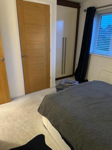 1 dormitorio con cama, armario y ventana en Cosy double bedroom with dedicated bathroom in Newcastle upon Tyne - Access to shared kitchen, shared lounge and shared conservatory areas inc Sky TV and Netflix, en Newcastle