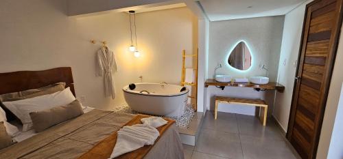 uma casa de banho com banheira e uma cama em pousada alkamar Quarto Luxo em Maragogi
