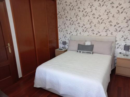 Un dormitorio con una cama blanca y una pared con flores en Apartamento Landra VUT-CO-003165, en Padrón