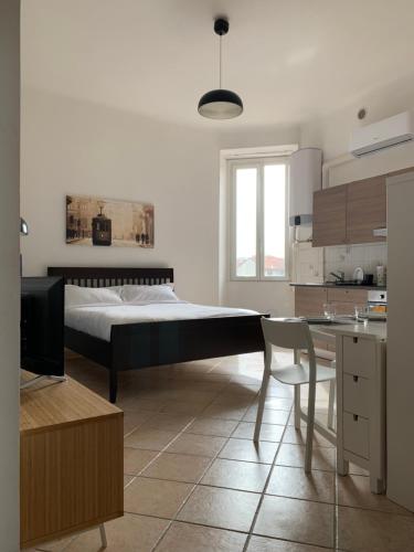 a bedroom with a bed and a table and a kitchen at Appartamento Baia del Re - Navigli in Milan