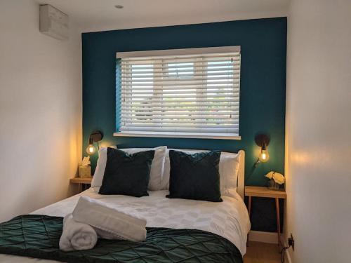Schlafzimmer mit einem Bett mit blauer Wand in der Unterkunft The Little Lodge in Horley