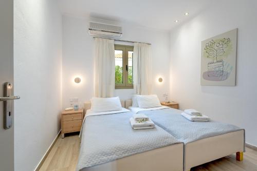 a white bedroom with two beds and a window at Eleonas Holiday Houses in Gialova