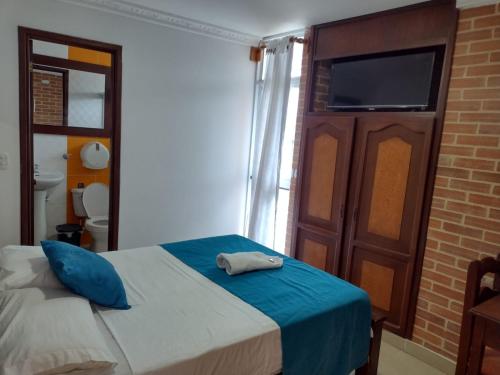 1 dormitorio con 1 cama con almohadas azules y TV en HOTEL NAPOLES, en Pitalito