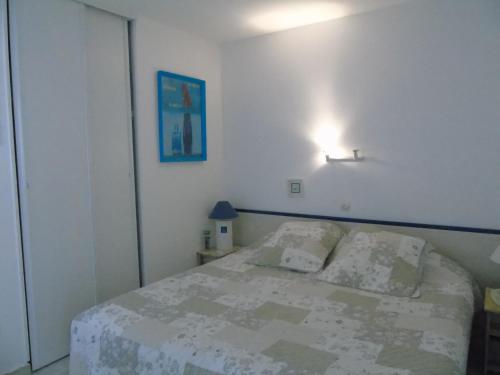 une chambre avec un lit et une lumière sur le mur dans l'établissement Le Pamplemousse, à Saint-Jean-de-Monts