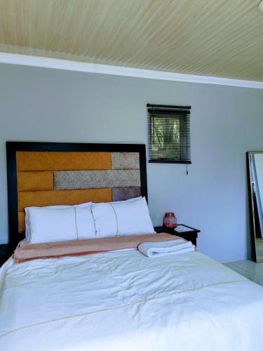 a bedroom with a large white bed with a wooden headboard at Sem's Guest Cottage in Edenvale