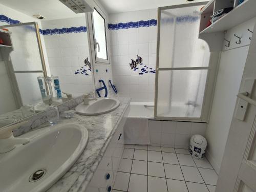 une salle de bain avec deux lavabos, une baignoire et une douche dans l'établissement L'Hollywood, à Saint-Jean-de-Monts