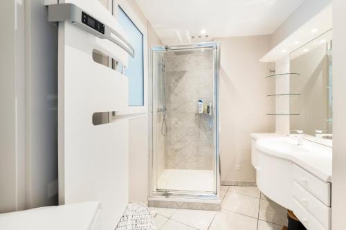 ein weißes Bad mit einer Dusche und einem Waschbecken in der Unterkunft HEOL, 5ème étage,Face mer in La Baule
