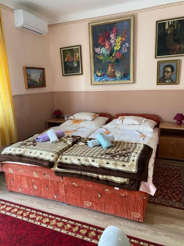 two beds in a bedroom with paintings on the wall at Károly Vendégház in Hévíz