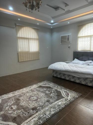 a bedroom with a bed and a rug and two windows at Alamjed Residence in Mecca