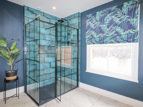 Una ducha de cristal en una habitación azul con ventana en Anglesey House, en Nantwich