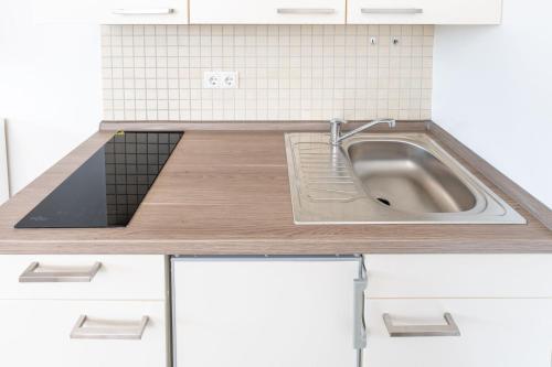 eine Küche mit einem Waschbecken und weißen Schränken in der Unterkunft Modernes Apartment mit privatem Stellplatz wenige Minuten von der Innenstadt & Mosel in Koblenz