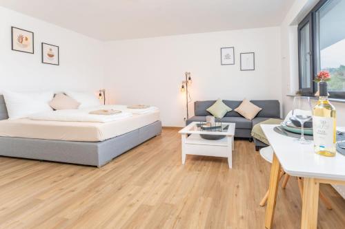 ein Schlafzimmer mit einem Bett und einem Sofa in der Unterkunft Modernes Apartment mit privatem Stellplatz wenige Minuten von der Innenstadt & Mosel in Koblenz