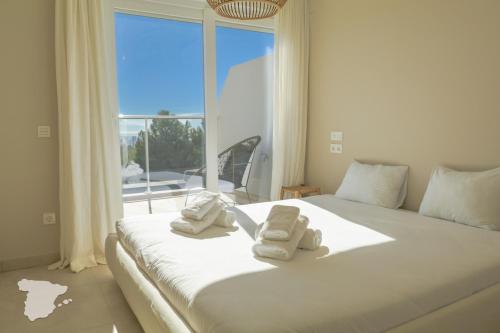 uma cama branca com toalhas e uma janela em CostaBlancaDreams Real Ifach Flora in Calpe em Calpe