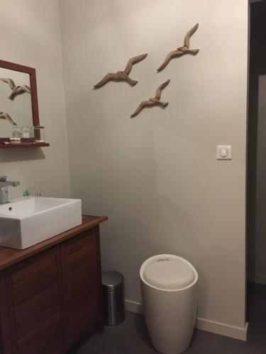La salle de bains est pourvue d'un lavabo et d'oiseaux sur le mur. dans l'établissement LA GLANERIE, à Le Touquet-Paris-Plage