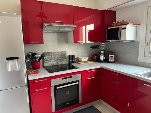 a red kitchen with white appliances and red cabinets at Appartement sans mauvaise surprises (2) in Juan-les-Pins