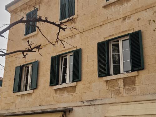 a building with green shuttered windows on it at Old Town Apartment in Omiš