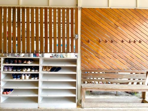 a bench in front of a wooden wall with shoes at Loju sunrise inn in Xiaoliuqiu