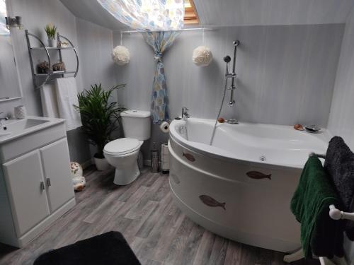 ein Badezimmer mit einer Badewanne, einem WC und einem Waschbecken in der Unterkunft Les quatre vents in Ars