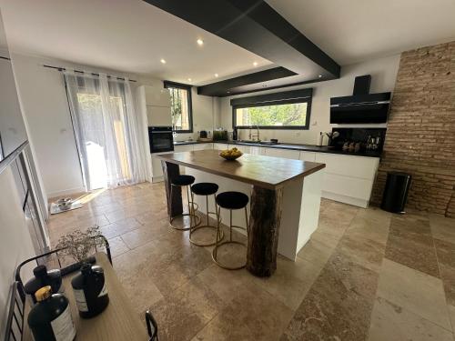 une cuisine avec un grand îlot en bois et des tabourets de bar dans l'établissement Chambre dans villa de standing, à Montaigut-sur-Save