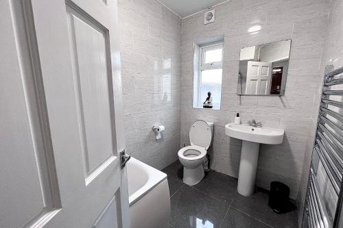 a white bathroom with a toilet and a sink at 3 Bedroom Holiday Home in Hackbridge