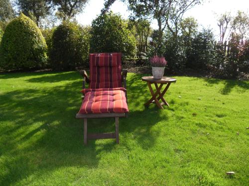 a red chair and a table in a yard at Haus-Seeschwalbe in Nieblum