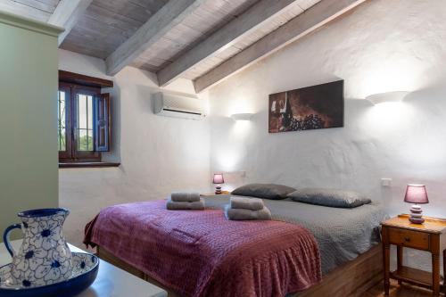 um quarto com uma cama com um cobertor roxo em Casa Uva española em Villanueva de la Concepción