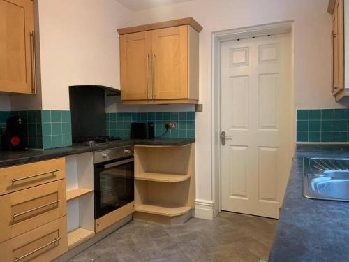 a kitchen with wooden cabinets and a sink at Central 2 bed flat with off street-parking in Bristol