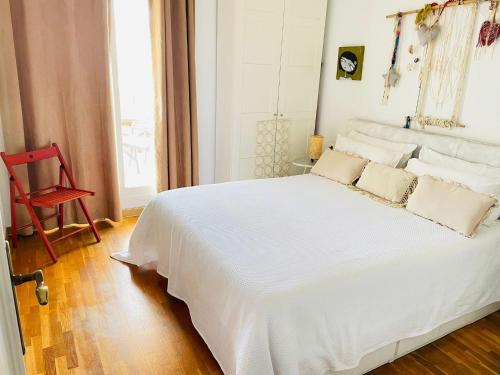 een wit bed in een kamer met een rode stoel bij Sweet Atic in Sitges