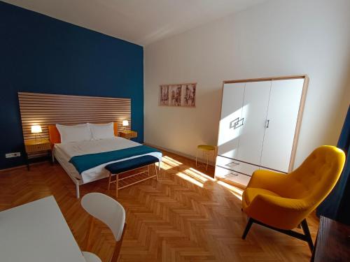 a bedroom with a bed and a yellow chair at PIF Apartments Hirscher in Braşov