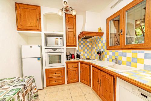 une cuisine avec des armoires en bois et un réfrigérateur blanc dans l'établissement Locations-06 L'Eugénie Gîte pour 8 au calme sur la Côte d'Azur, à Le Bar-sur-Loup