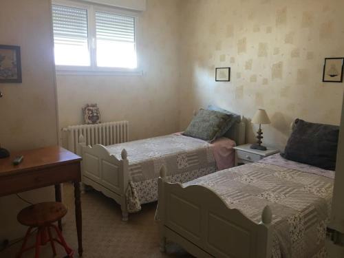 une chambre avec deux lits, une table et un bureau dans l'établissement Grande maison 40m de la plage de Pontaillac, à Royan
