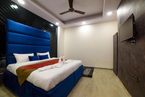 a bedroom with a blue bed with a flat screen tv at The Twenties Kamla Nagar in New Delhi