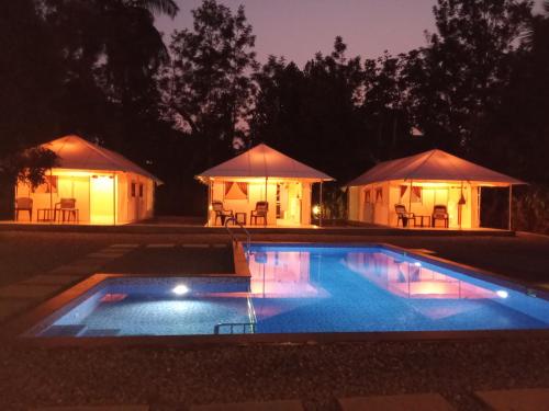 a swimming pool in front of tents at night at Torch Ginger Homestay in Sultan Bathery