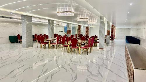 a dining room with red chairs and tables in a building at Raksha Suites & Banquet Greater Noida in Greater Noida