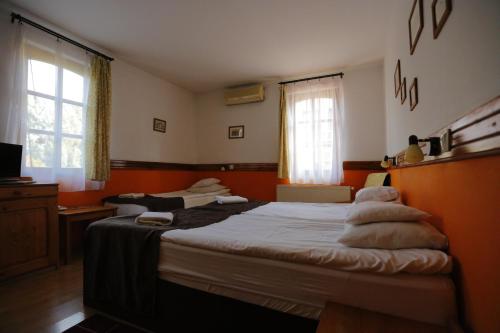 a bedroom with two beds with orange walls and a window at Hotel Szent István in Eger