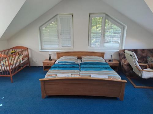 Schlafzimmer mit einem Bett, einem Kinderbett und Fenstern in der Unterkunft Ferienhaus für 12 Personen und 3 Kinder in Vranov, Böhmen 
