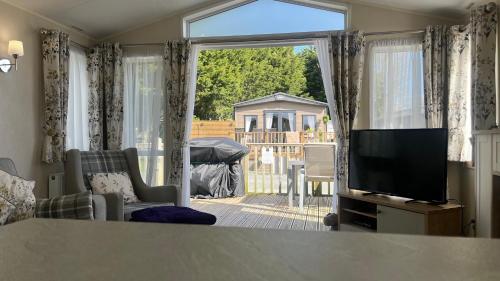 a living room with a television and a large window at Dog Friendly Lodge with hot tub Quiet Location in Great Eccleston
