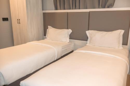 2 camas en una habitación con sábanas y almohadas blancas en Starry Beach Inn, en Hulhumale
