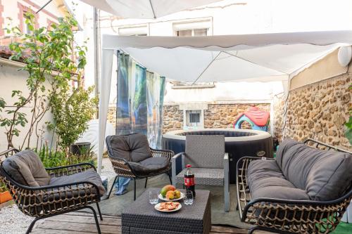 une terrasse avec des chaises, une table et un parasol dans l'établissement Jacuzzi extérieur à 15 min de Paris*, à Rosny-sous-Bois