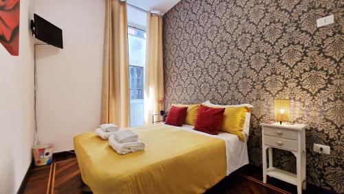 ローマにあるMyomax Guesthouseのベッドルーム1室(黄色いシーツと赤い枕のベッド1台付)