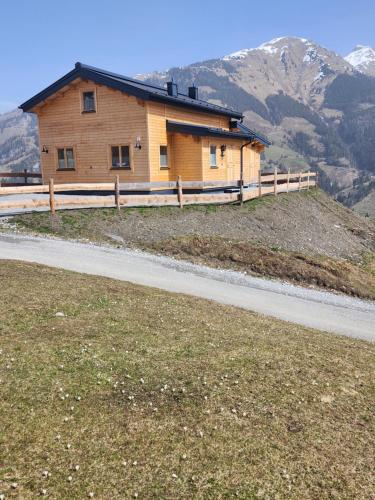 a wooden house on a hill with a road at Lipphütte Top Lage mit traumhafter Aussicht in Rauris