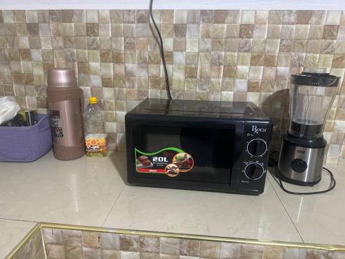 a black microwave sitting on a counter with a blender at Winnie's Home in Morogoro