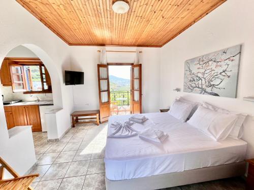 a bedroom with a white bed with a wooden ceiling at Nicolas Studios in Skala
