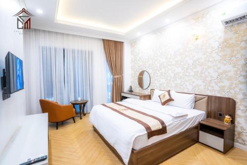 um quarto de hotel com uma cama grande e uma cadeira em Chuly Moon Motel em Hà Tiên
