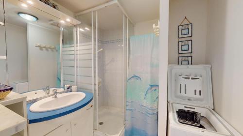 une salle de bain blanche avec un lavabo et une douche dans l'établissement Le Jardin de la mer 150 plage, à Plage-des-Demoiselles