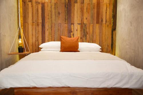 a bed with an orange pillow on top of it at Flores Passport House in Ende